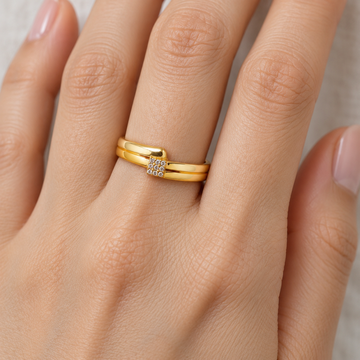 AI-generated try-on simulation of a 21K gold double-rail ring with a small rectangular cluster of clear stones.