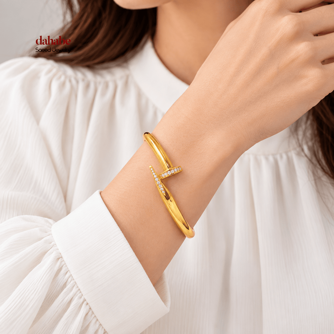 AI-generated try-on of a 21K yellow gold zircon-studded nail bangle bracelet on a model’s wrist