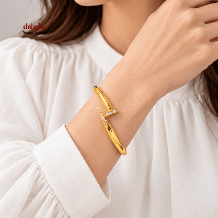 AI-generated try-on of a 21K yellow gold zircon-studded nail bangle bracelet on a model’s wrist